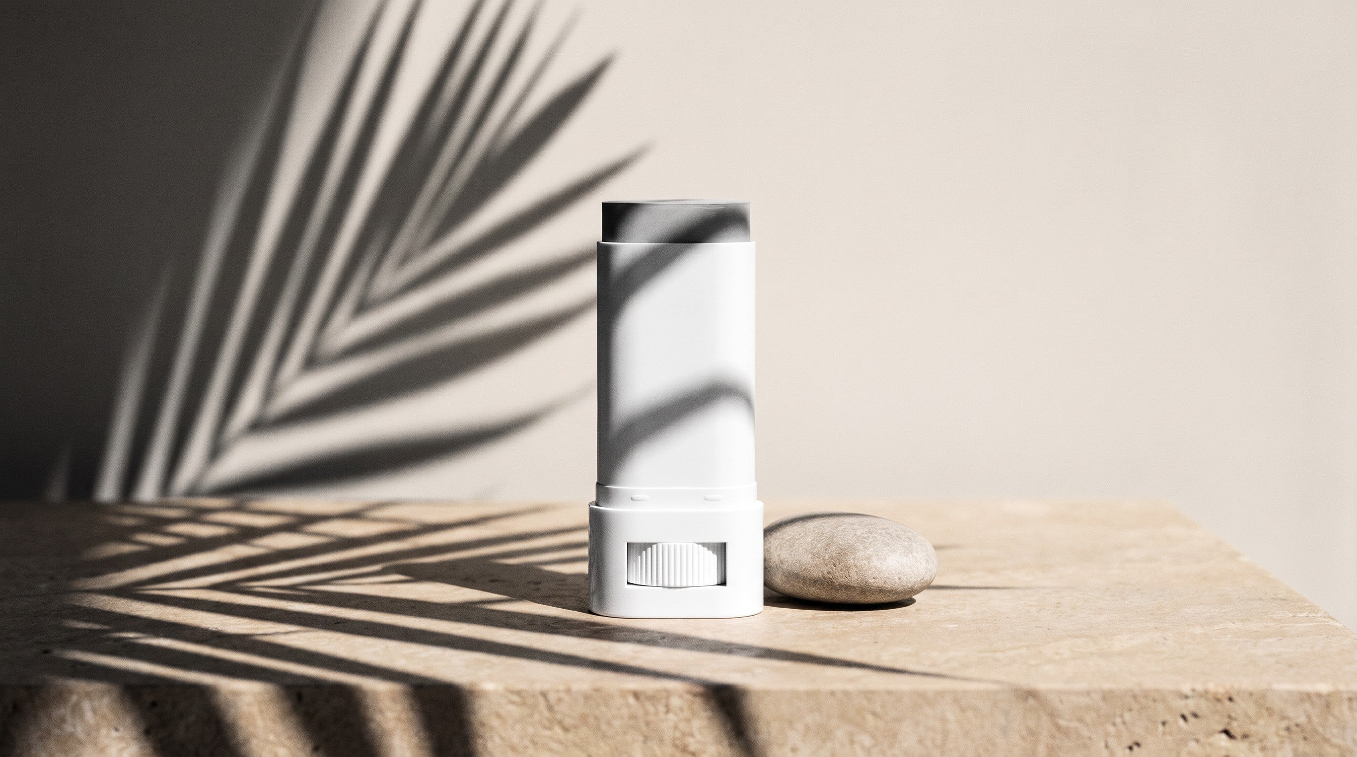 Tinted mineral sunscreen stick SPF50 in a white tube on a sunlit stone surface