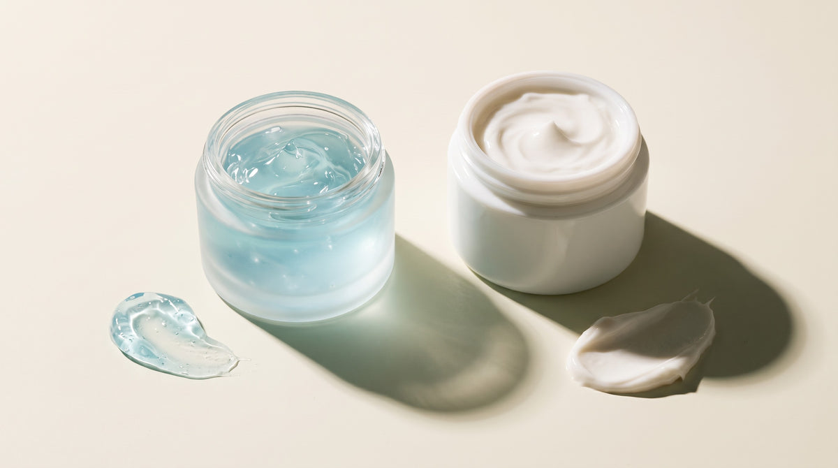 Gel moisturizer vs cream moisturizer — a translucent blue hydrating gel in a glass jar beside a thick white cream, with swatches of each texture